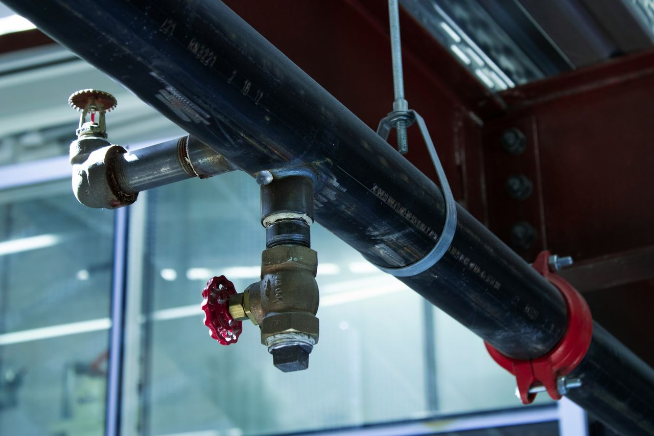 A sprinkler pipe with a pendant head running below a steel beam.