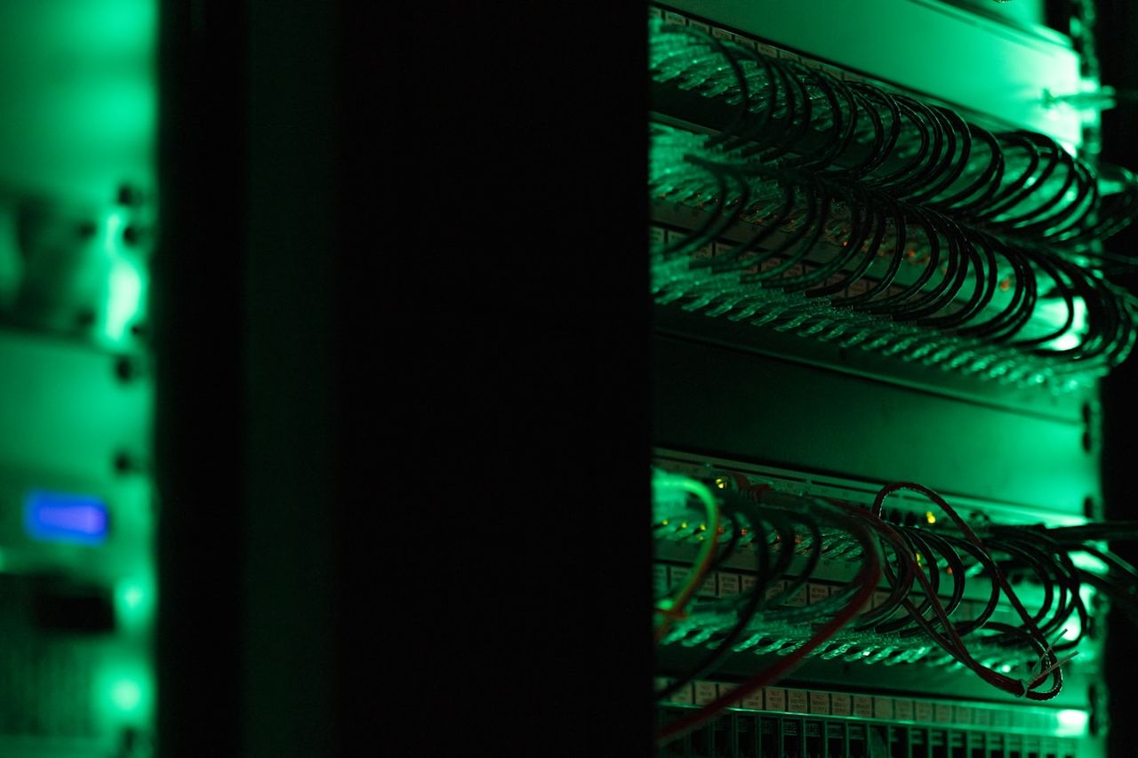 Network racks and patch panels in a dark equipment room.
